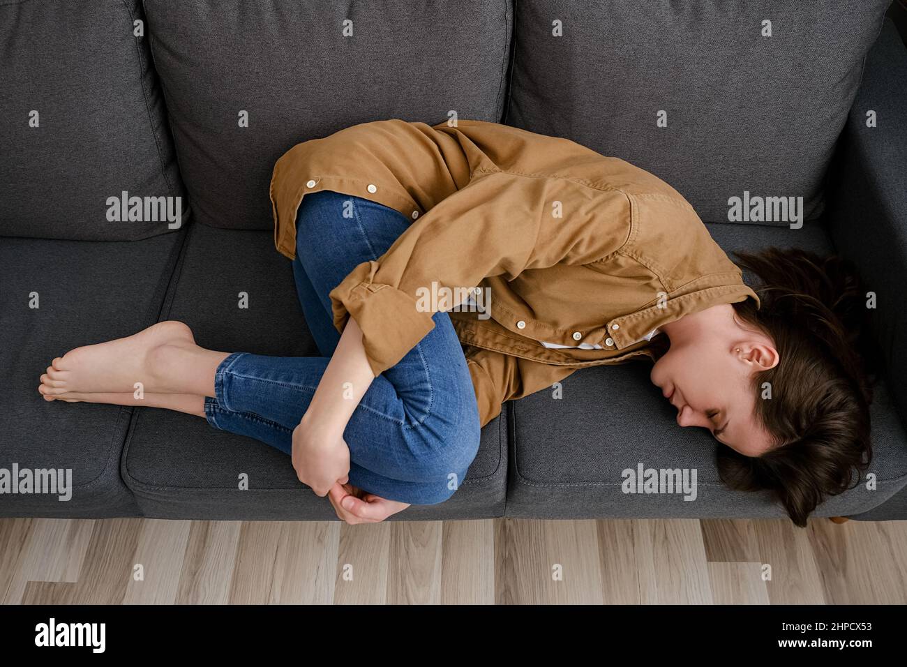 Vue de dessus de la jeune femme malheureuse et fatiguée couché sur un canapé maudé souffre de crampes menstruelles. Grossesse non planifiée et avortement, essayez de dormir Banque D'Images