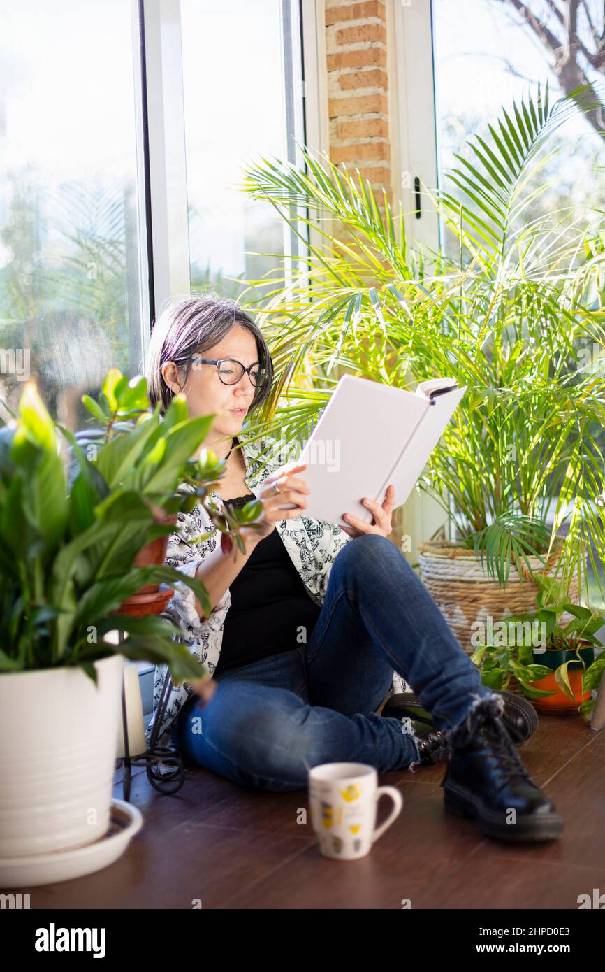 Femme adulte lisant un livre sur la terrasse du jardin. Concept de vie quotidienne à la maison. Banque D'Images