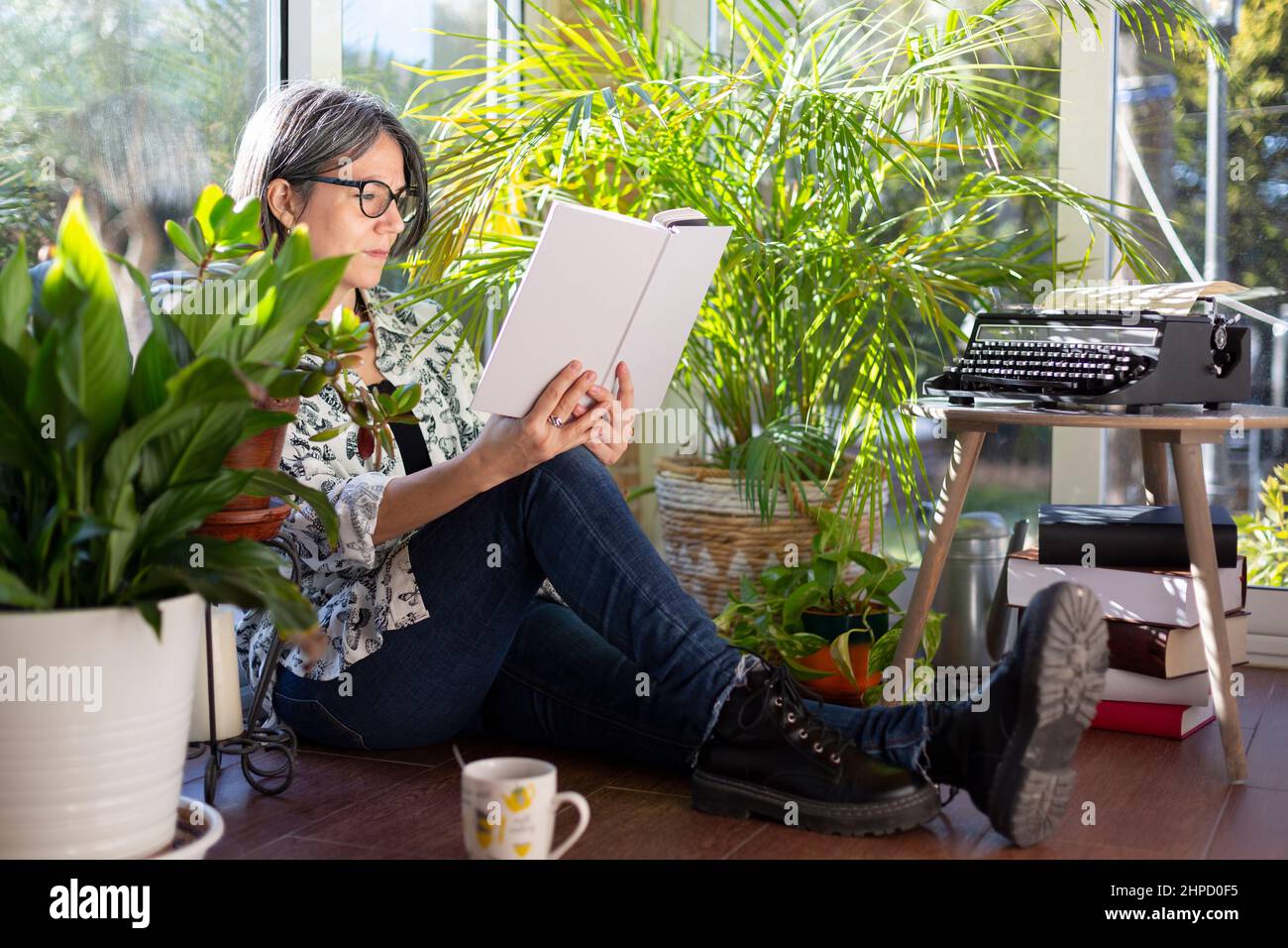 Femme adulte appréciant le plaisir de lire sur la terrasse du jardin. Bien-être à la maison. Banque D'Images