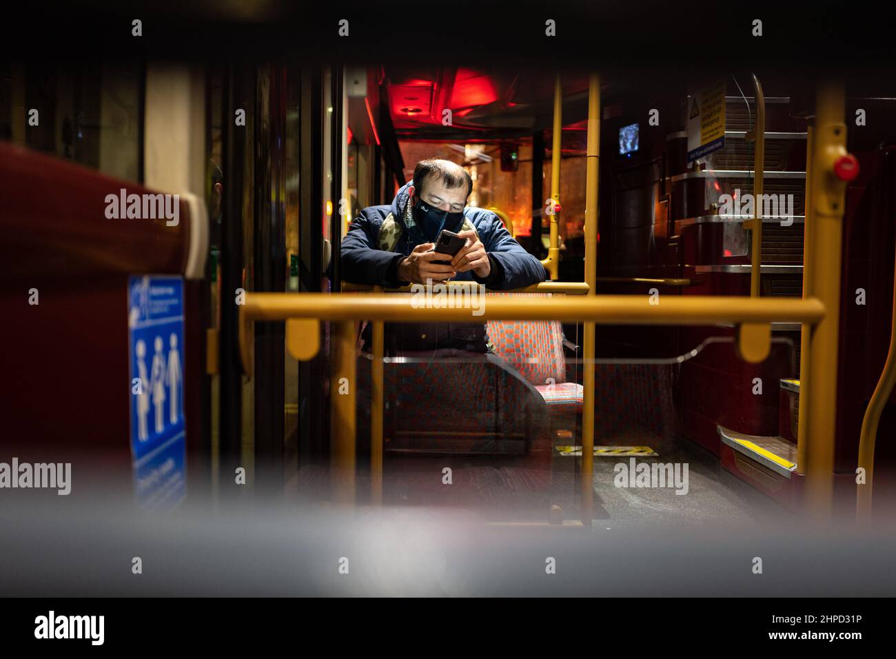 Photo d'un passager sur un bus londonien lisant son téléphone portable. Londres, Royaume-Uni Banque D'Images