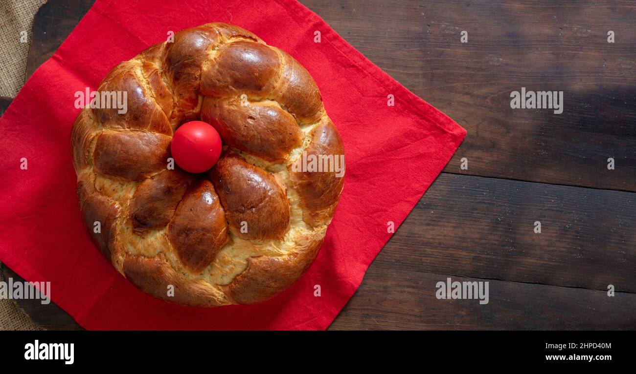 Pain de Pâques sucré, vue sur le haut de la tresse grecque tsoureki. Brioche ronde avec décoration aux œufs et serviette rouge sur fond de bois Banque D'Images
