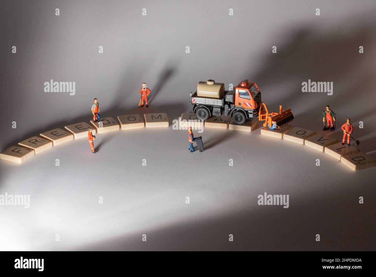 Des personnages miniatures nettoyant la rue COVID, la rue du jour de la liberté apparaissant après eux Banque D'Images