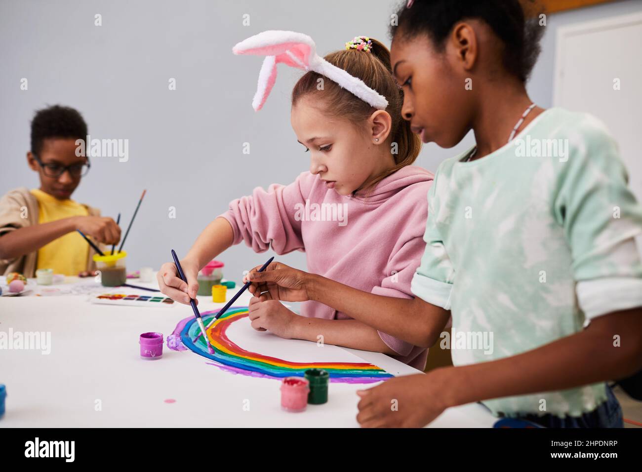 Portrait de deux petites filles dessinant l'arc-en-ciel à la table d'art et d'artisanat tout en appréciant la fête de Pâques pour les enfants Banque D'Images