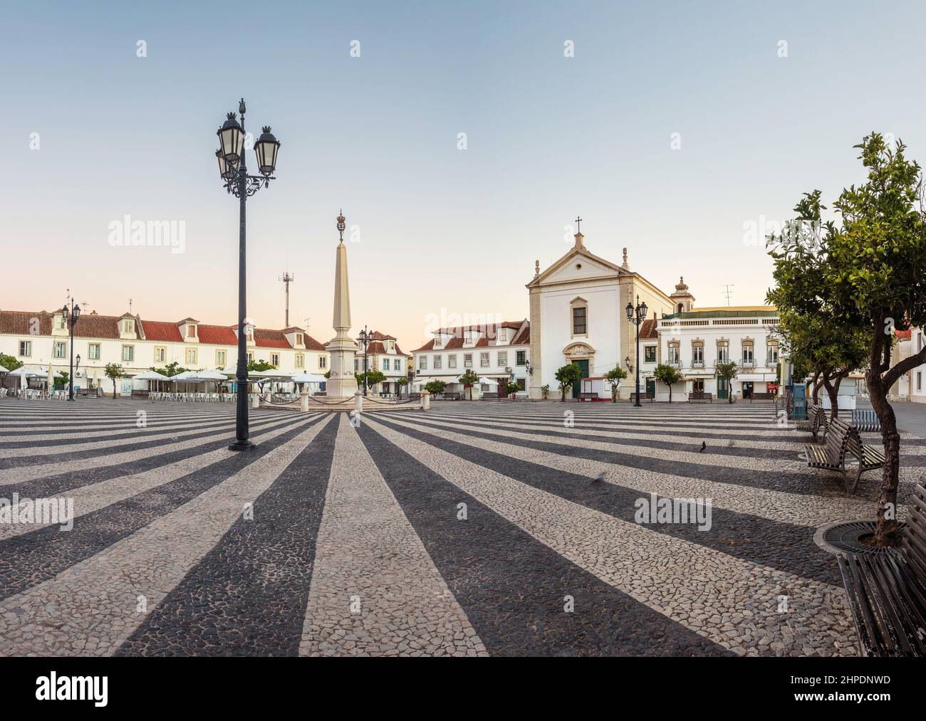 Lever du soleil sur la place Marquês de Pombal à Vila Real de Santo António, Algarve, Portugal, avec l'oblique au centre de la place. Banque D'Images