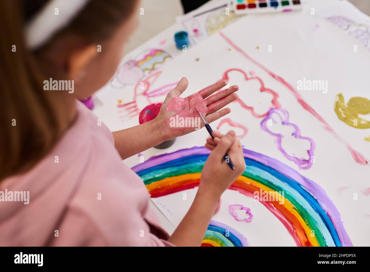 Gros plan de la petite fille dessin arc-en-ciel tout en appréciant la peinture de doigt à la fête de Pâques pour les enfants, copier l'espace Banque D'Images