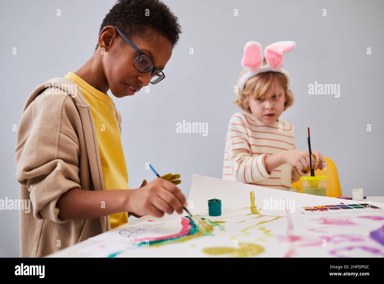 Portrait d'un garçon afro-américain sur une table d'art et d'artisanat tout en profitant d'une fête d'intérieur pour les enfants Banque D'Images