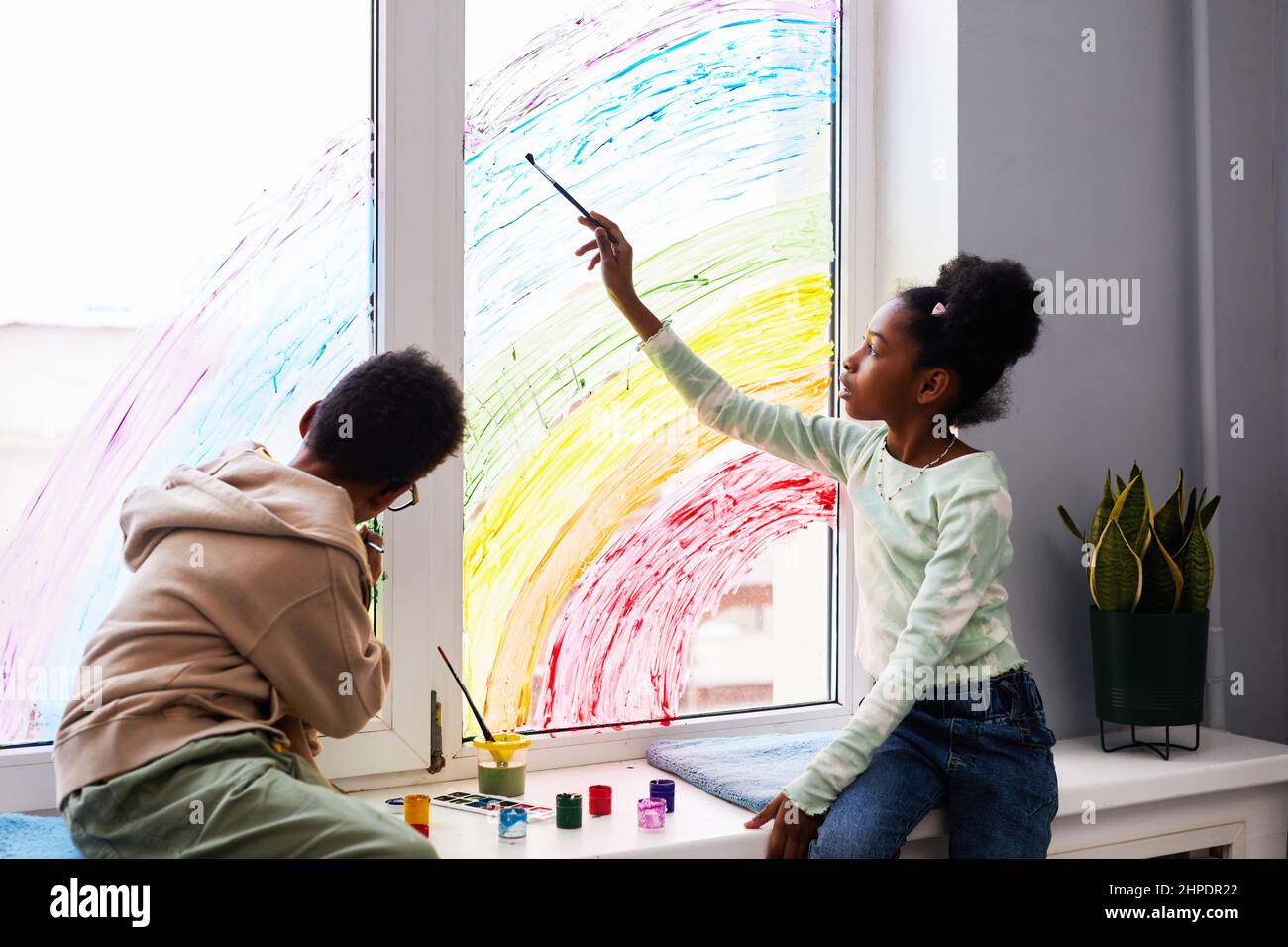 Portrait de deux enfants afro-américains dessinant avec de la peinture sur les fenêtres tout en décorant la chambre des enfants ensemble Banque D'Images