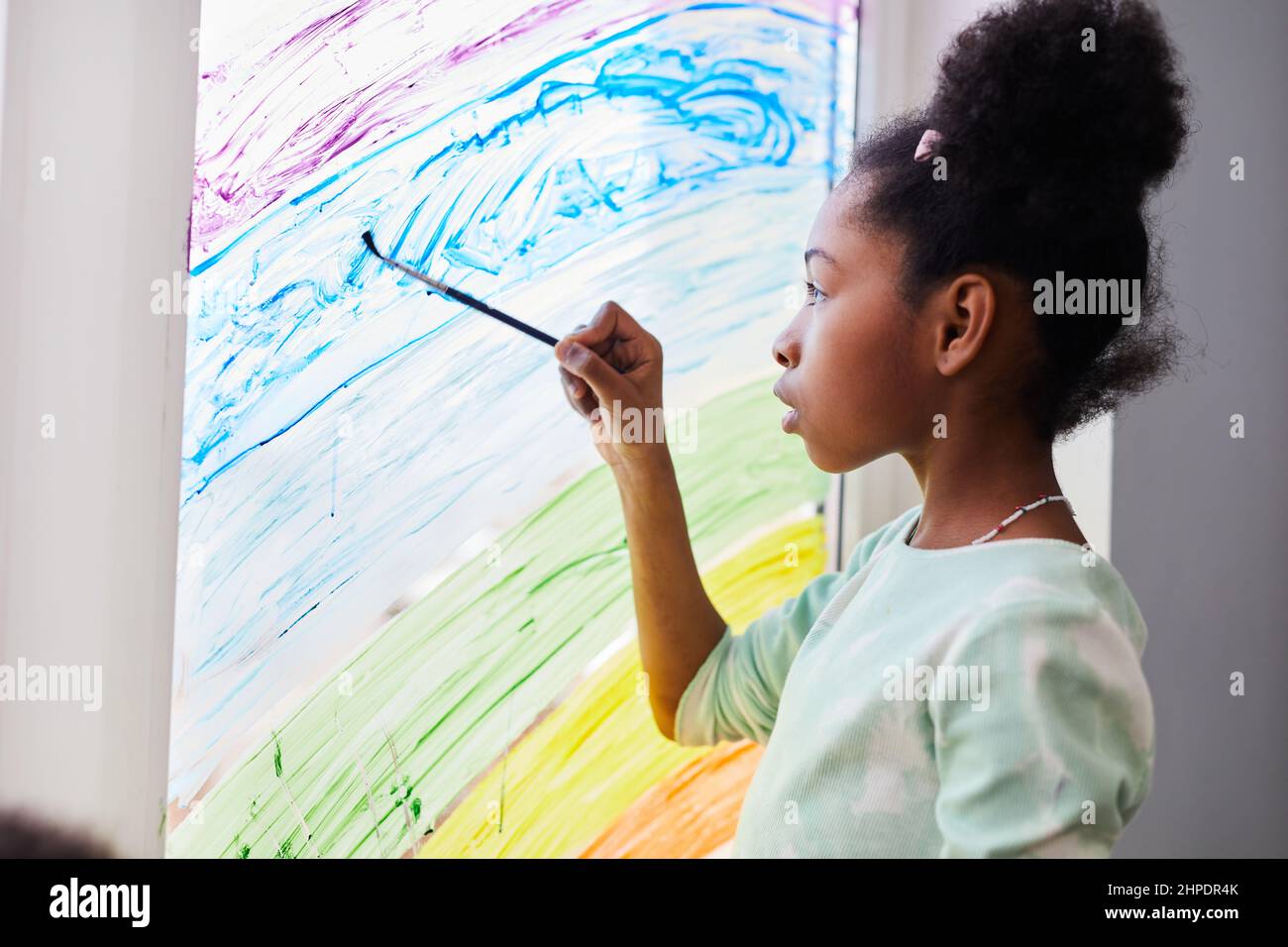 Portrait d'une fille afro-américaine dessin avec de la peinture sur les fenêtres tout en décorant la chambre des enfants, copier l'espace Banque D'Images