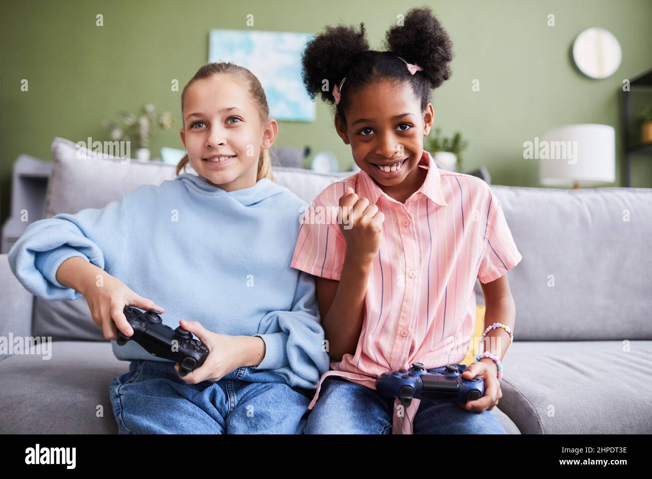 Portrait de deux filles jouant à des jeux vidéo à la maison et s'amusant à l'intérieur, espace de copie Banque D'Images