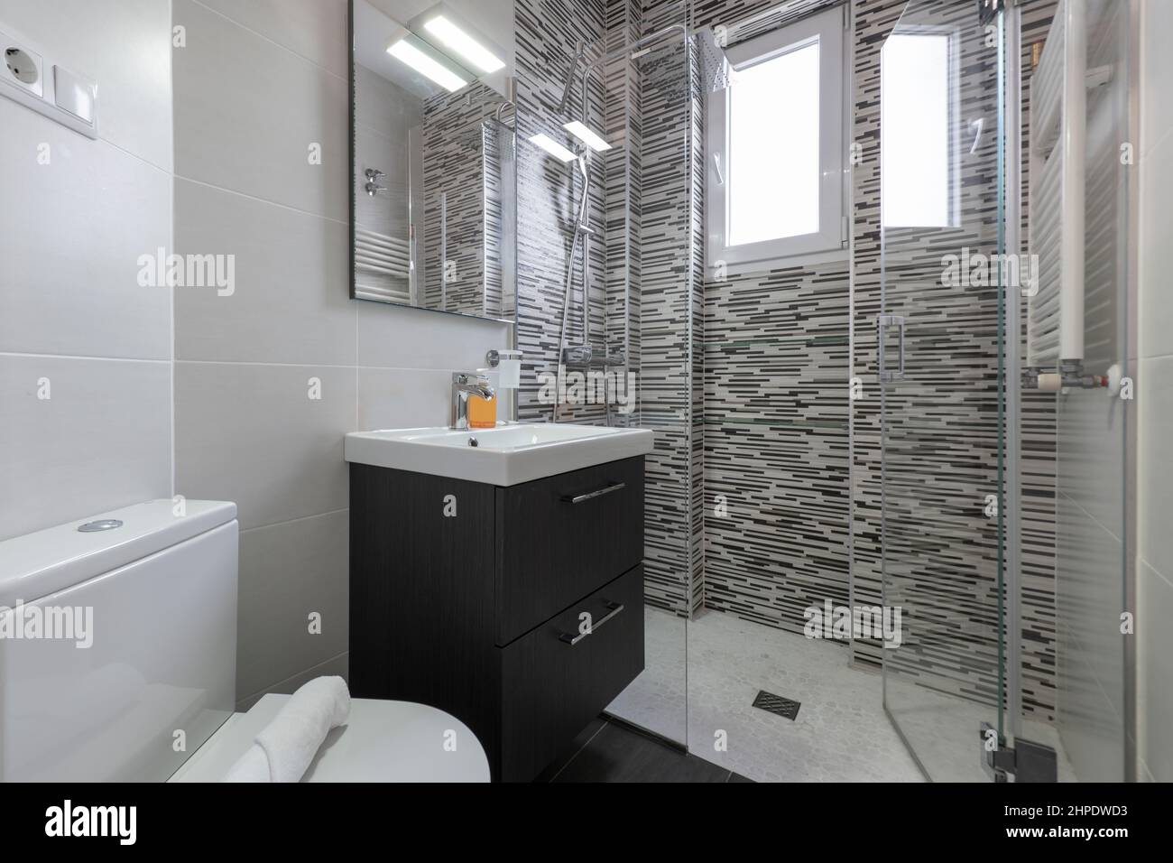 Lavabo avec armoire en bois sombre et douche avec cloison en verre et évier en porcelaine blanche Banque D'Images