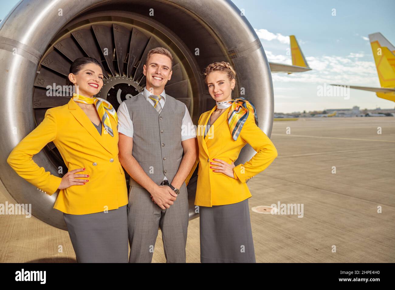 Des employés de compagnie aérienne souriants se tenant près du moteur à turbine de l'avion Banque D'Images