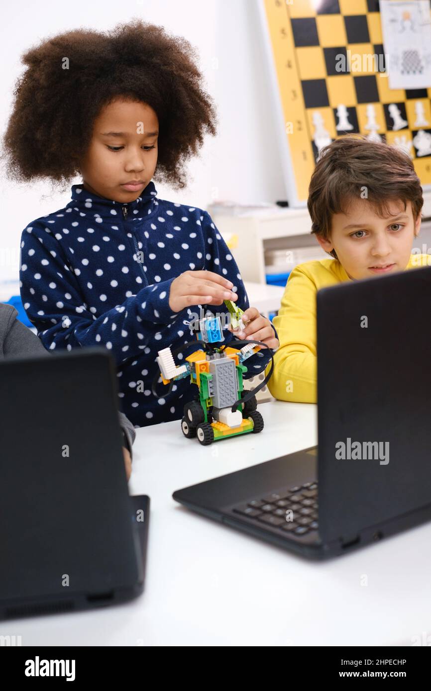 Les enfants apprennent le codage, la science et la technologie en classe scolaire. Des enfants afro-américains et caucasiens ont été cloués avec des ordinateurs portables dans la LEÇON STEM Banque D'Images