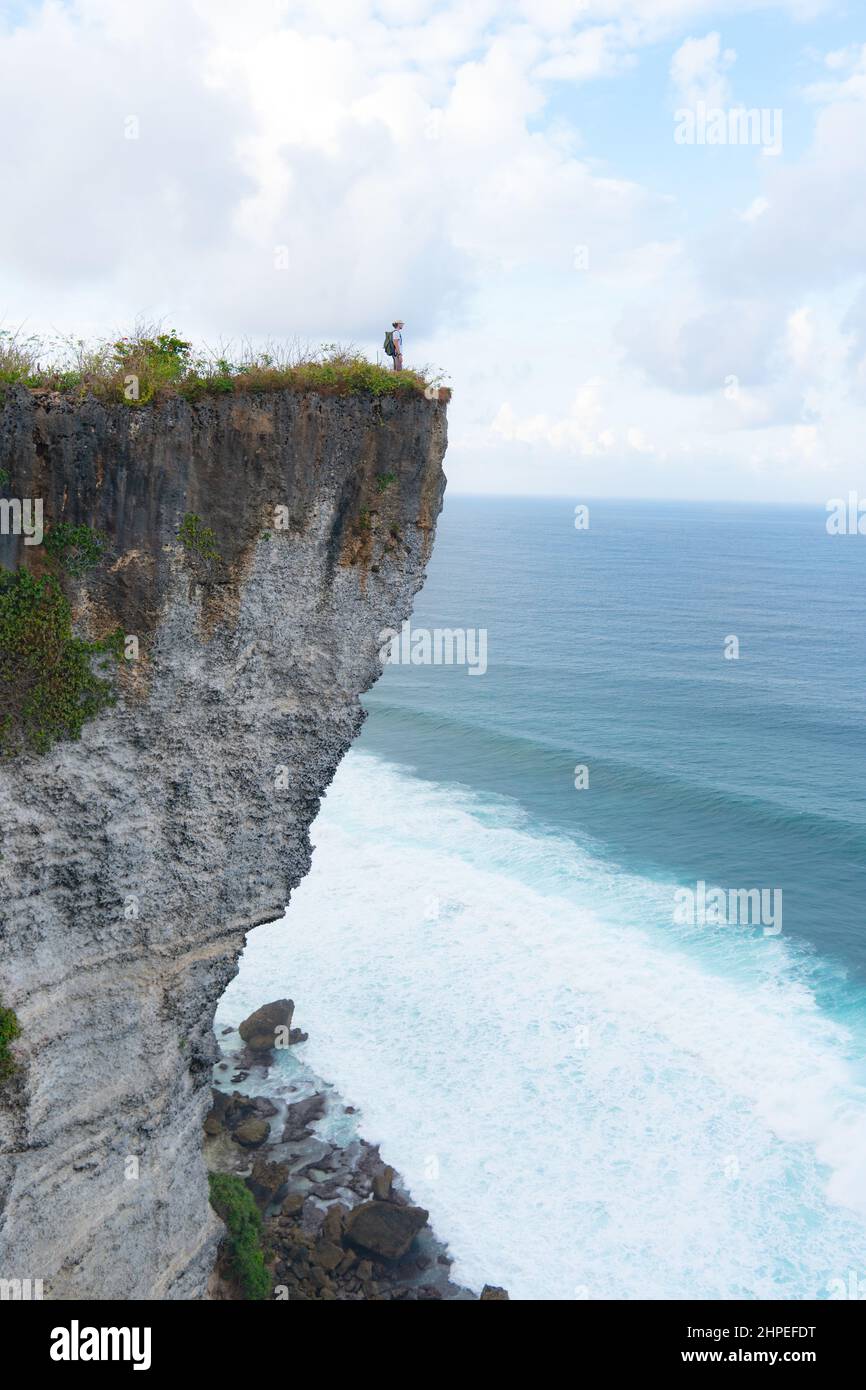 un homme debout sur une falaise qui regarde l'océan Banque D'Images