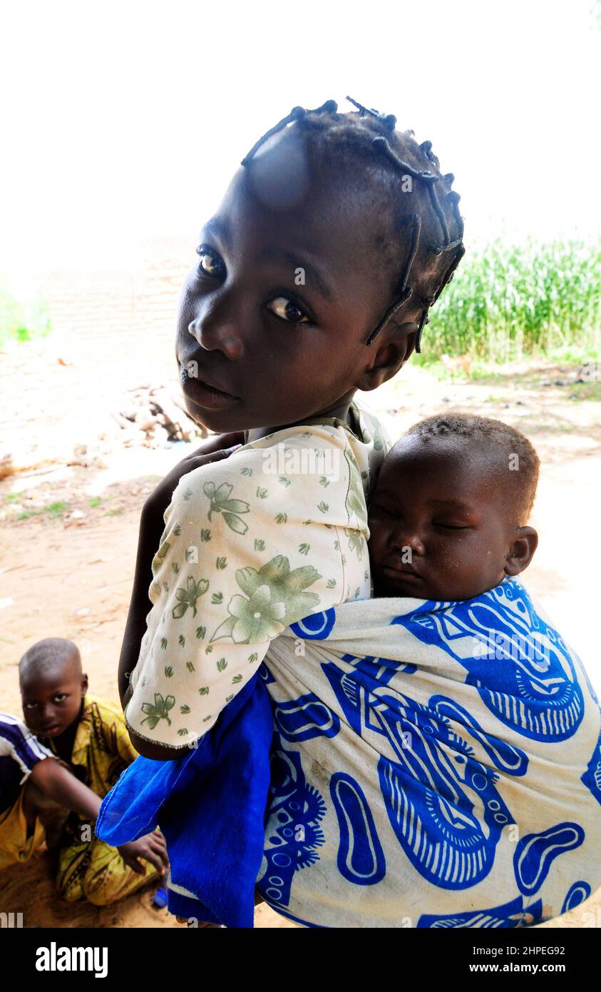 Une fille burkinabe portant son petit frère sur le dos. Centre du Burkina Faso. Banque D'Images