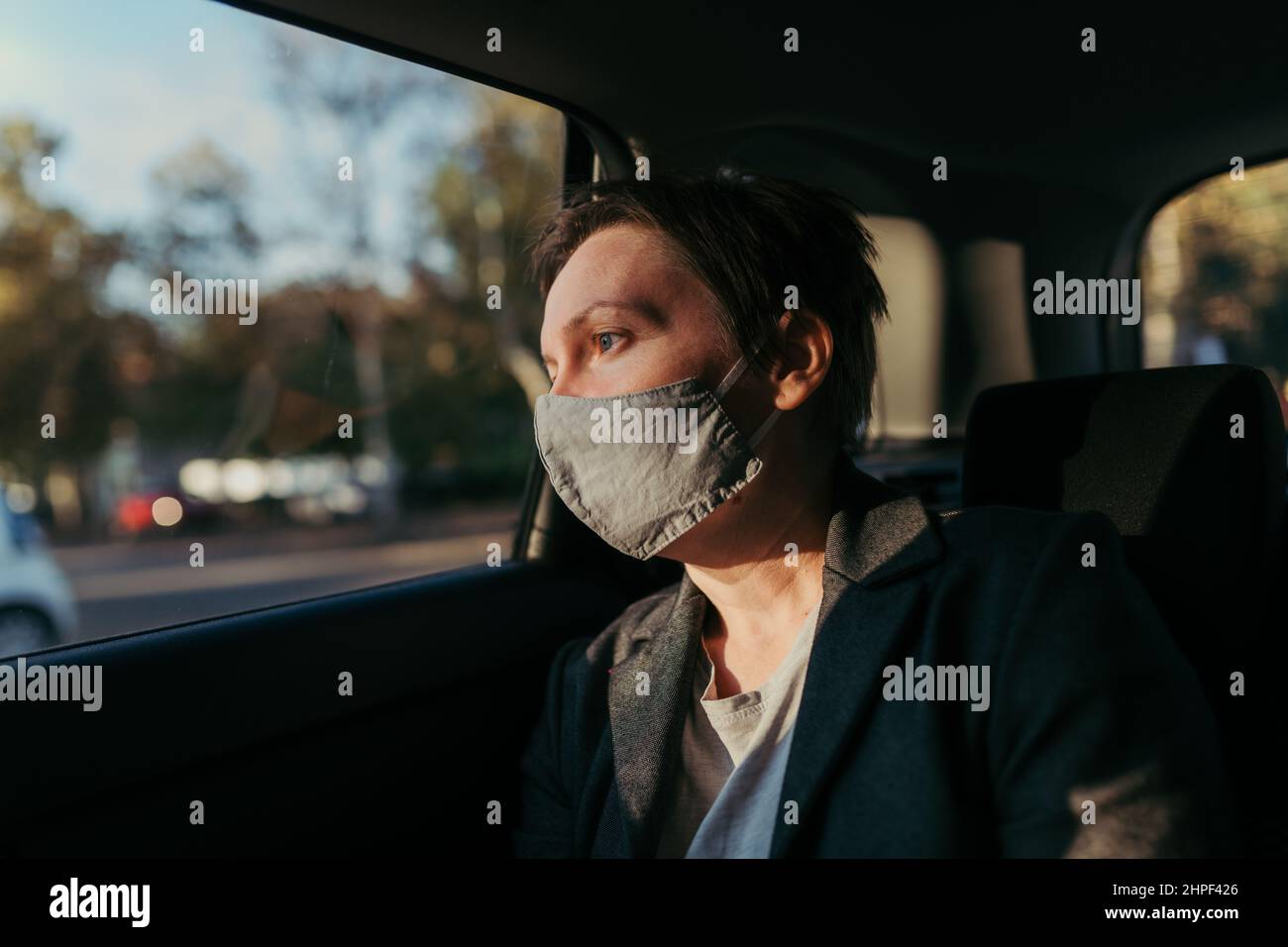 Femme d'affaires inquiète avec masque de protection dans la voiture et regardant par la fenêtre, foyer sélectif Banque D'Images