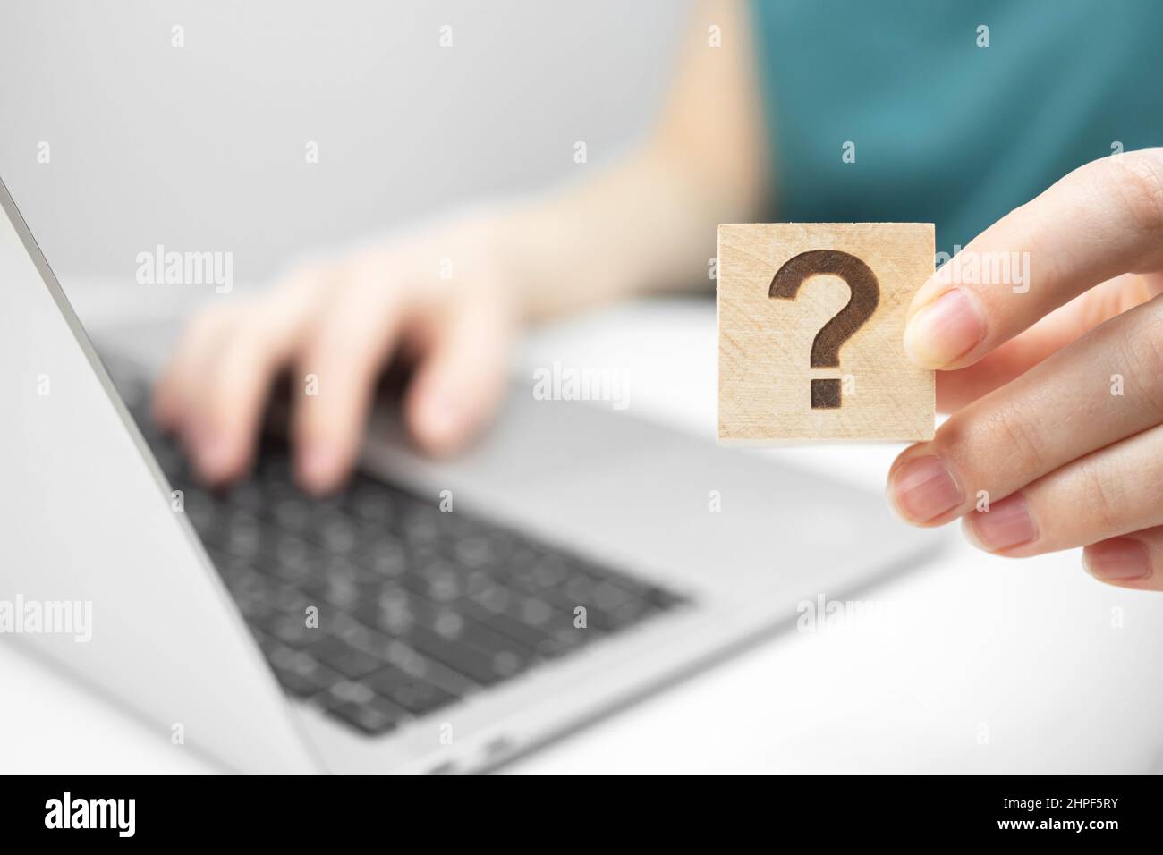 Présentation du concept de service à la clientèle et d'assistance. FAQ icône de point d'interrogation sur un cube en bois vue rapprochée, ordinateur portable sur une table de bureau blanche photo Banque D'Images