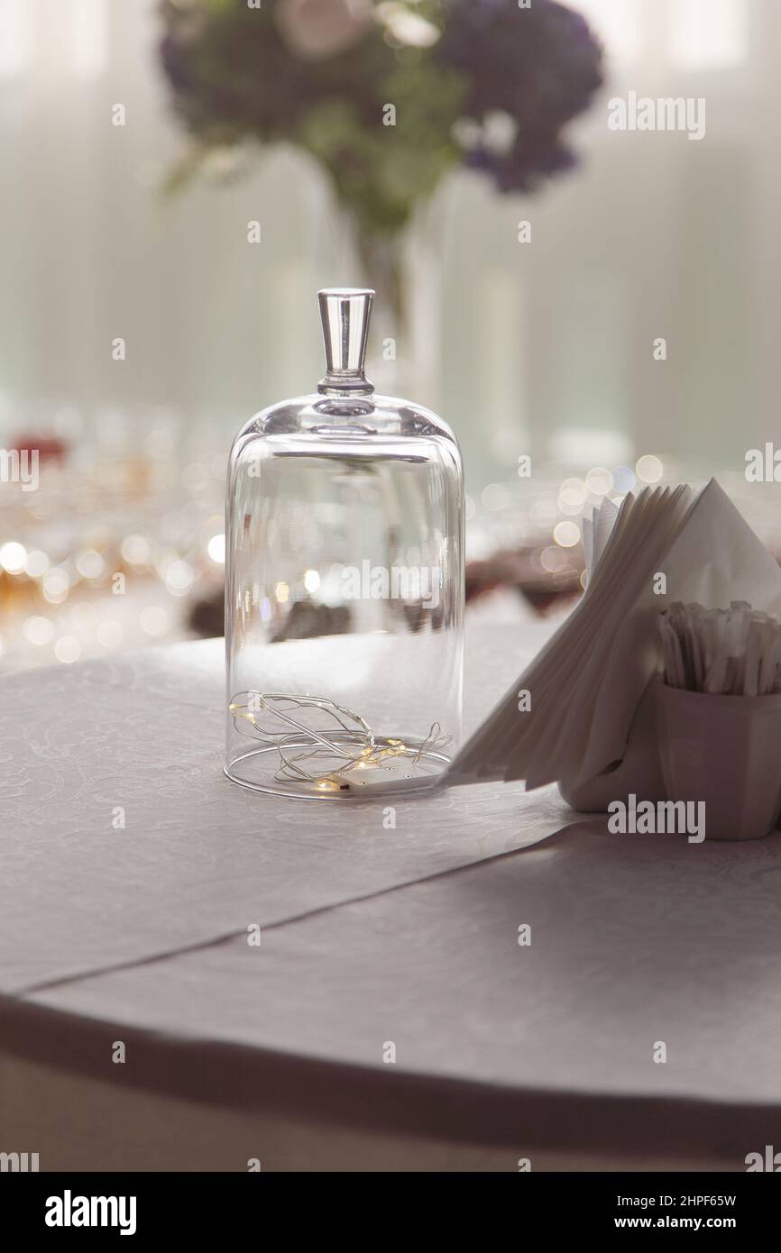 Lumières de fées sous un dôme en verre placé sur la table avec des serviettes en papier dans le café comme décoration de Noël Banque D'Images