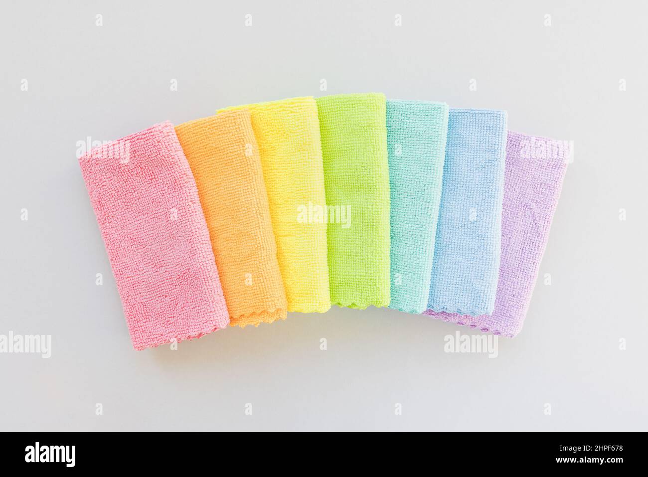 Nouveau chiffon en microfibre plié pour un nettoyage dans sept couleurs arc-en-ciel sur fond gris. Nettoyage des microserviettes en tissu pour épousseter et polir. Concept de service de nettoyage domestique. Vue de dessus, espace de copie Banque D'Images