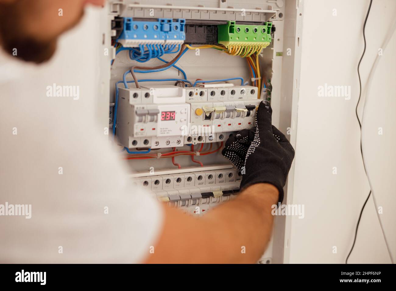 Main du technicien en électricité travaillant avec les fusibles au niveau de l'armoire de commande du disjoncteur sur le mur Banque D'Images
