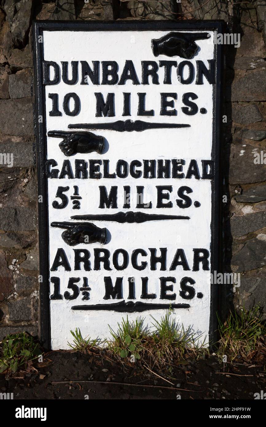 Marqueur de mille métallique peint en noir et blanc à Rhu indiquant la distance jusqu'aux villes locales, Dunbarton, Garelochhead et Arrochar, à Argyll, en Écosse Banque D'Images