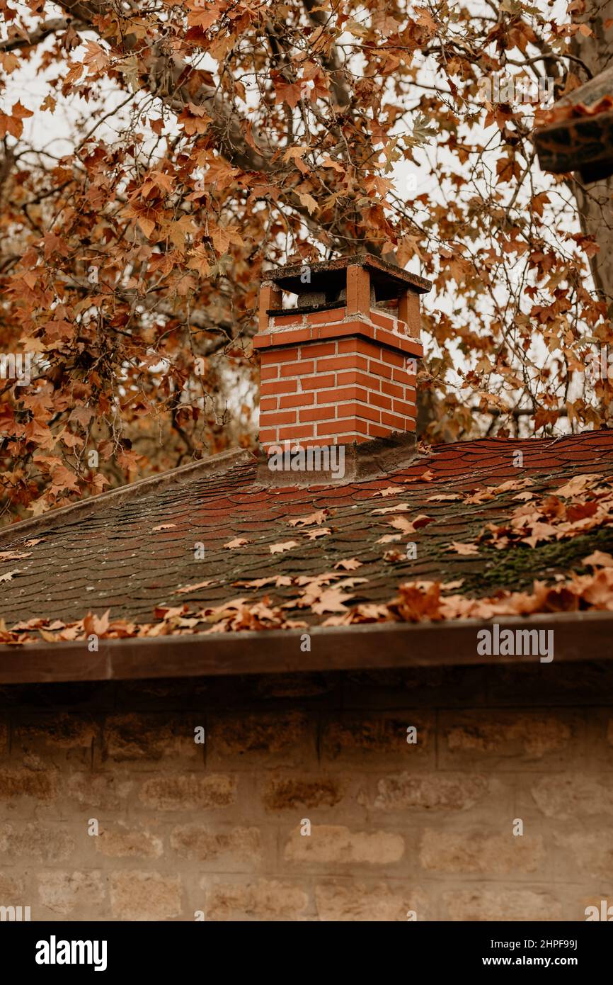 Feuilles séchées et cheminée en briques sur le toit en automne. Gros plan Banque D'Images
