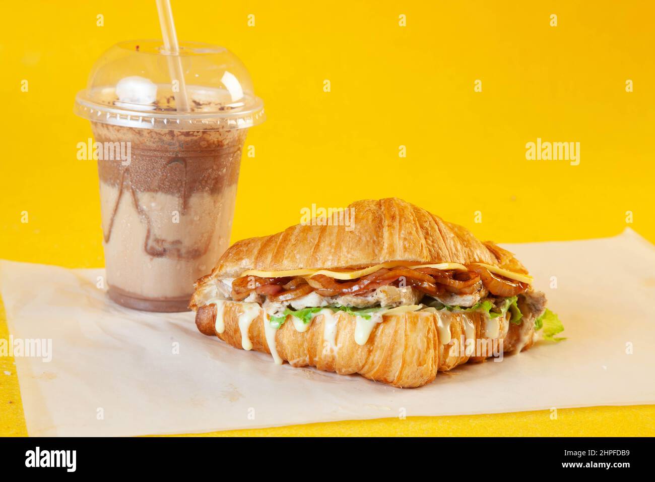 Sandwich croissant aux brioches de poulet grillées avec latte glacée et mini-beignet fourré. Banque D'Images