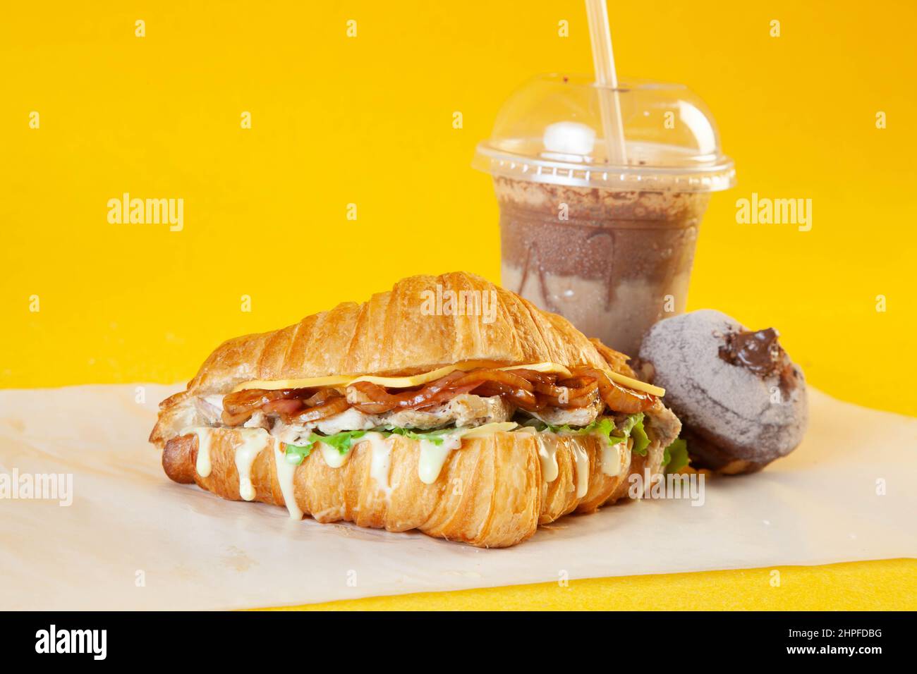 Sandwich croissant aux brioches de poulet grillées avec latte glacée et mini-beignet fourré. Banque D'Images