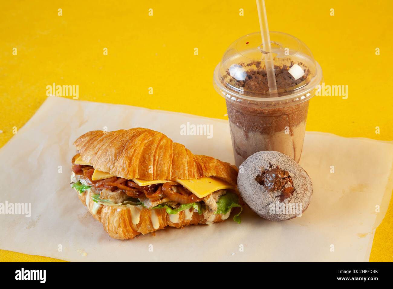 Sandwich croissant aux brioches de poulet grillées avec latte glacée et mini-beignet fourré. Banque D'Images
