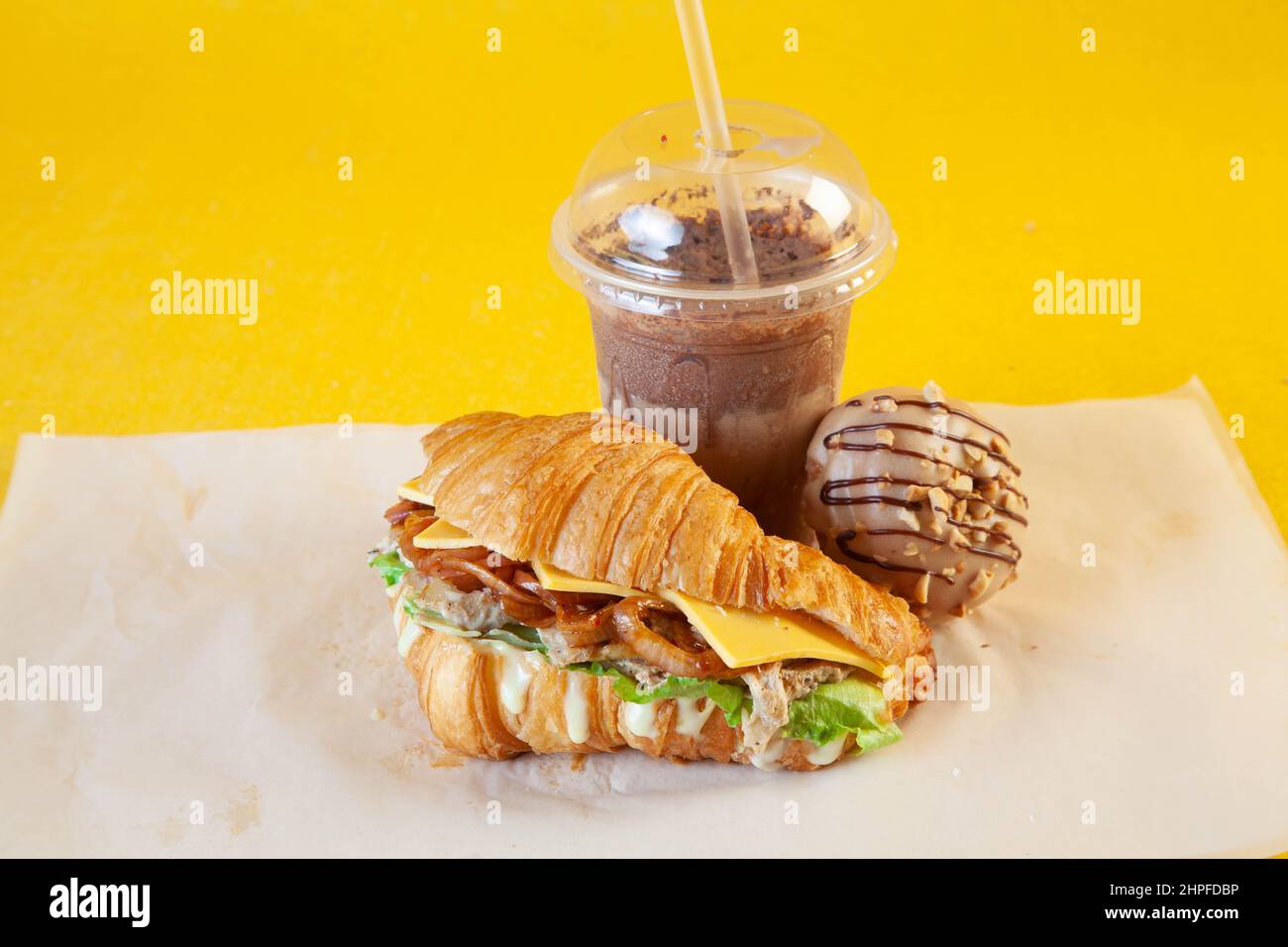 Sandwich croissant aux brioches de poulet grillées avec latte glacée et mini-beignet fourré. Banque D'Images