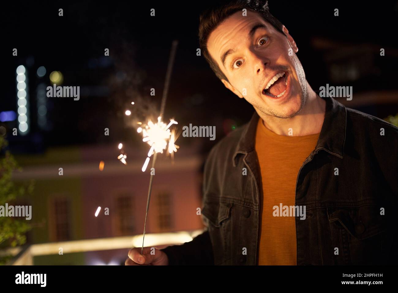 Homme caucasien tirant visage drôle à la caméra. Tenue d'une soirée de fête sur le toit. Banque D'Images