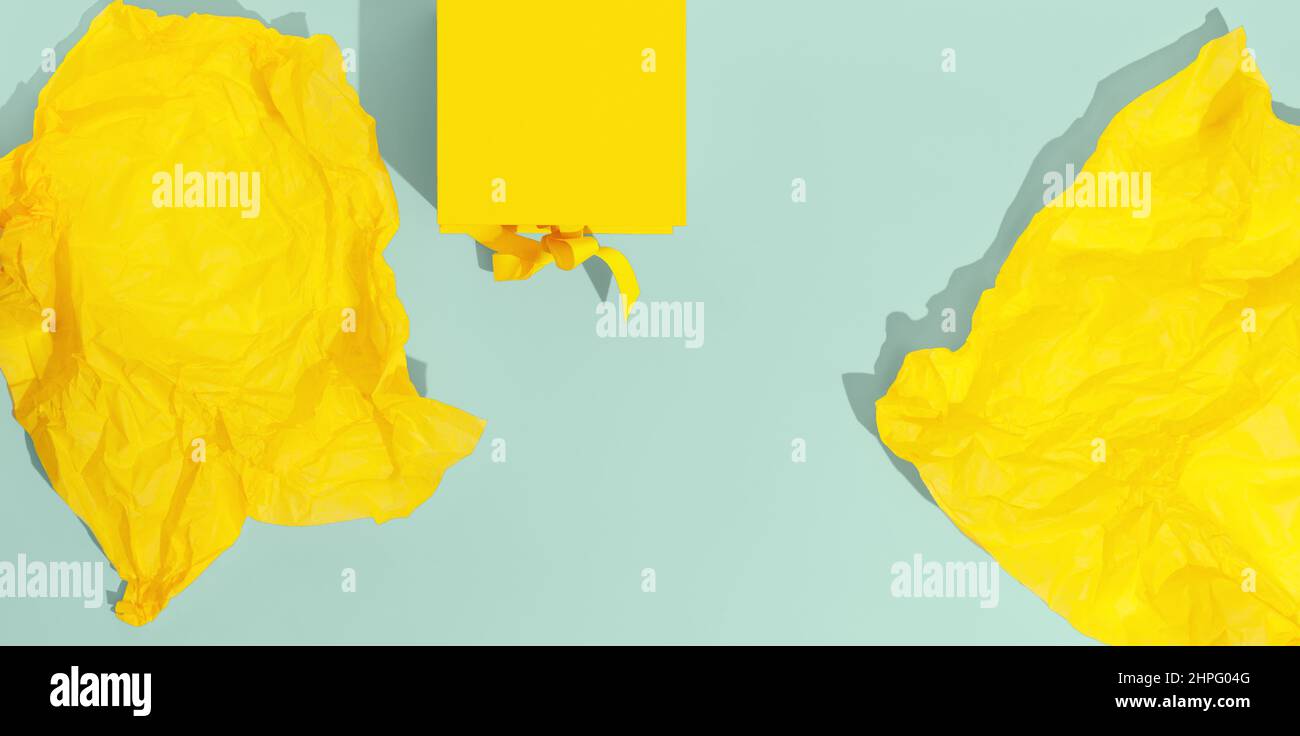 Boîte-cadeau jaune vif avec noeud en ruban et papier d'emballage sur fond bleu clair vue du dessus de l'espace de copie. Cadeau d'anniversaire, 8 mars, Fête des mères, Valen Banque D'Images