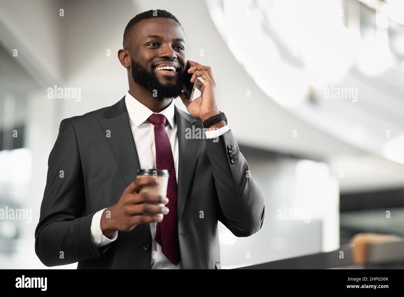 Bon directeur noir regardant avoir une conversation téléphonique, boire du café Banque D'Images