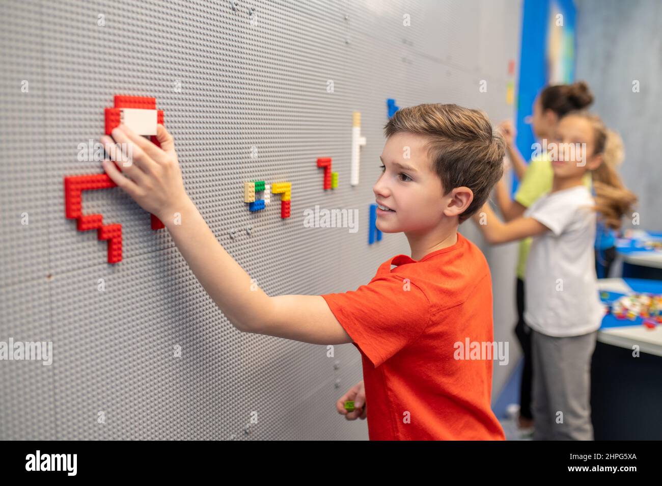 Les garçons et les filles font un puzzle lego sur le mur Banque D'Images