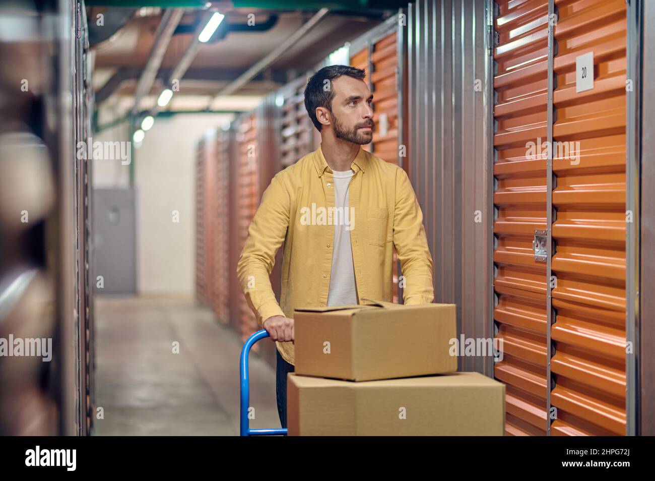 L'employé qui fait rouler le chariot d'entrepôt avec des marchandises emballées Banque D'Images