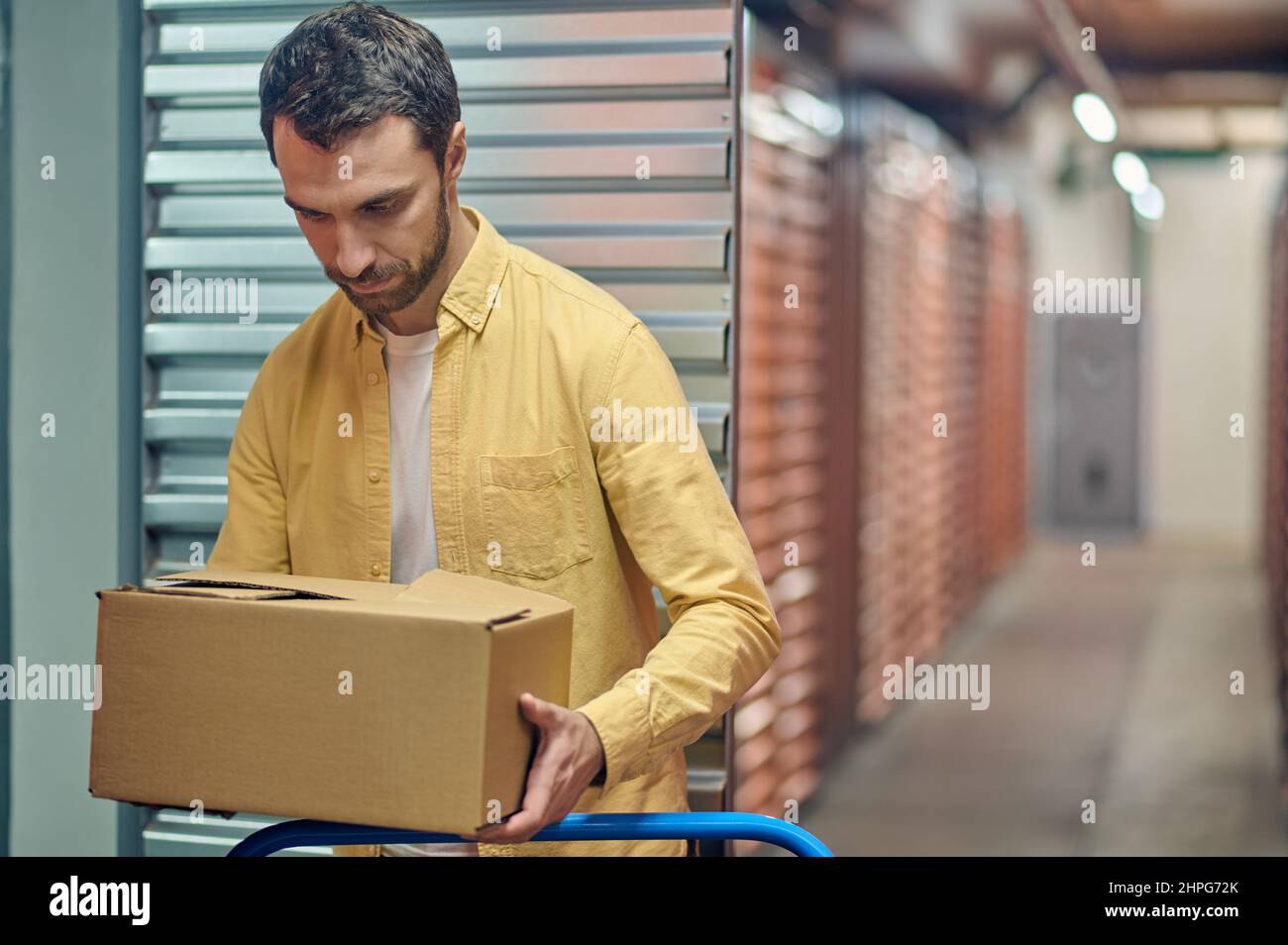 Travailleur concentré plaçant des marchandises en boîte sur le chariot Banque D'Images