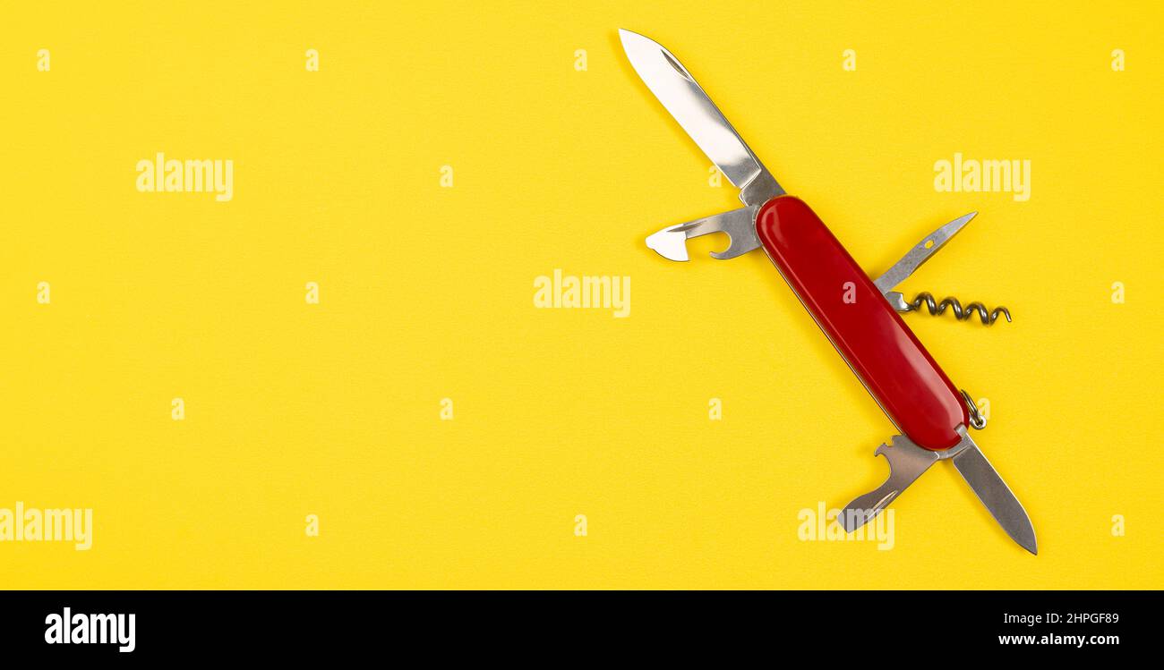 Jack de tous les métiers concept avec l'armée suisse multi péages couteau de poche isolé sur fond jaune. Couteau militaire rouge avec espace de copie Banque D'Images