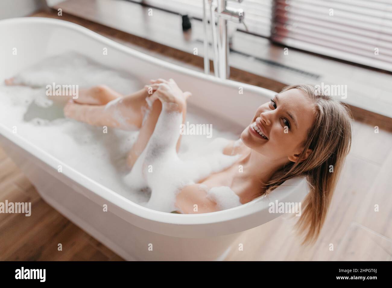 Jeune femme détendue prenant le bain avec de la mousse, souriant à  l'appareil photo, se reposant dans la baignoire chaude le matin à la maison  Photo Stock - Alamy
