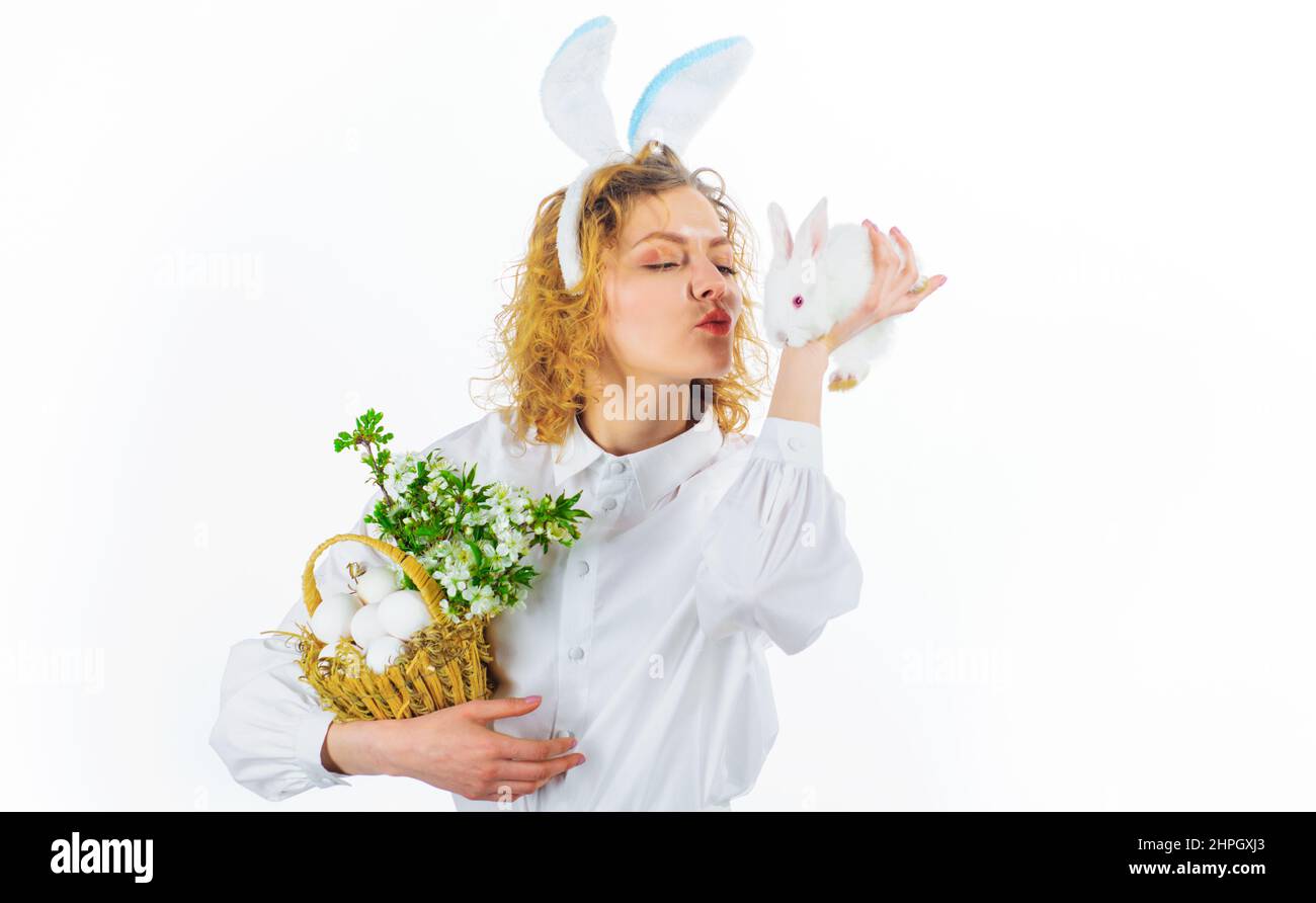 Fille dans les oreilles de lapin avec des oeufs de panier embrassant le petit lapin. Bonne journée de Pâques. Chasse aux œufs Banque D'Images