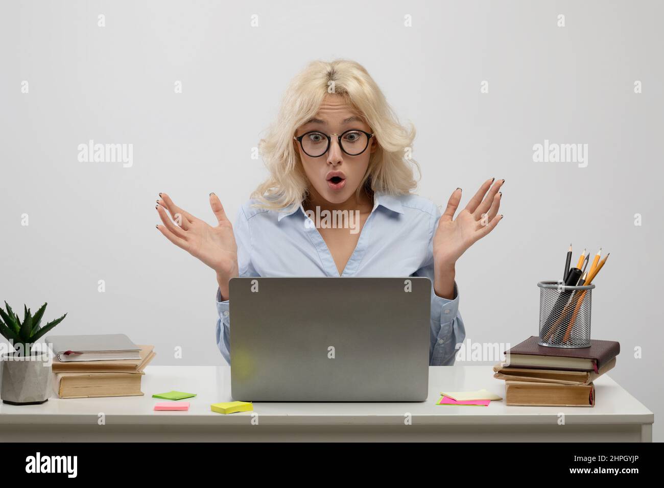 Femme d'affaires émotive regardant l'écran d'un ordinateur portable en état de choc, employée de bureau assise sur le lieu de travail, arrière-plan léger Banque D'Images