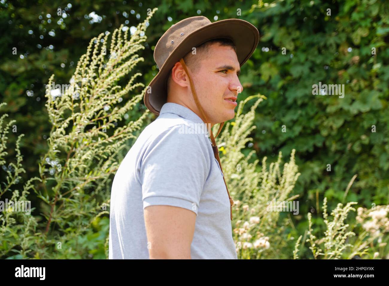 Homme en chapeau.Portrait d'un fermier souriant avec de l'herbe verte et de la nature des arbres en arrière-plan.Jeune homme portant un chapeau de cow-boy sur le terrain.Gros plan.Joyeux jeune p Banque D'Images