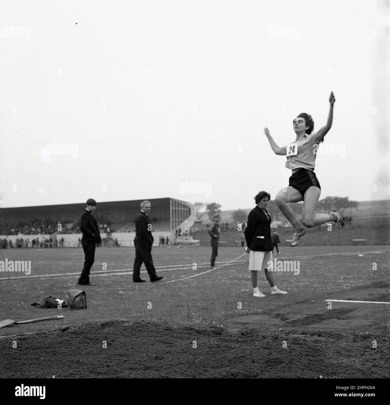 1960s, historique, une athlète féminine à mi-parcours faisant le long saut, Fife, Écosse, Royaume-Uni. La vitesse, la force et l'agilité sont toutes nécessaires dans cet événement sur piste et sur le terrain, où l'objectif est de sauter le plus loin possible d'un point de décollage. Les femmes ont pris part pour la première fois au long saut olympique en 1948 à Londres. Banque D'Images