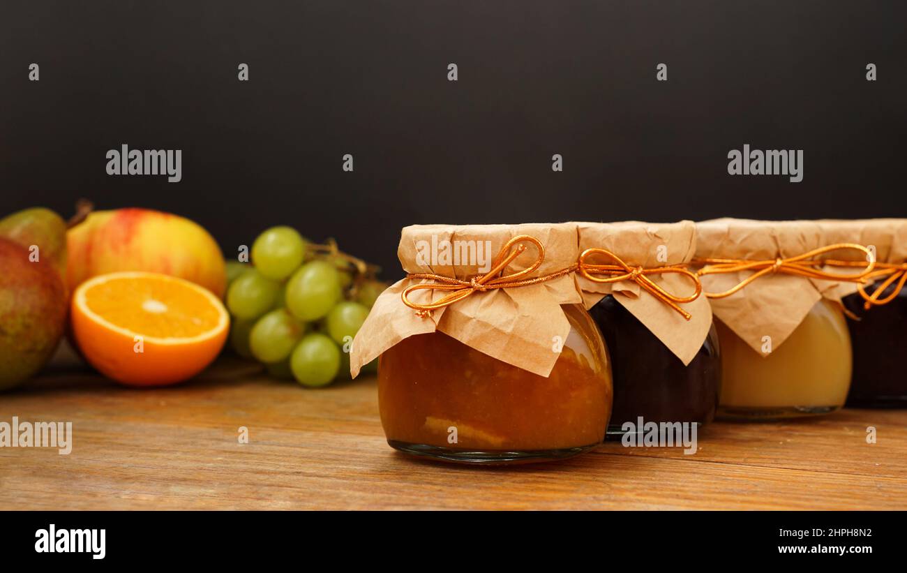 Confiture maison, mise au point sélective. Bocaux confits. Dessert sucré. Des fruits flous en arrière-plan. Raisin, orange, pomme. Marmelade maison Banque D'Images