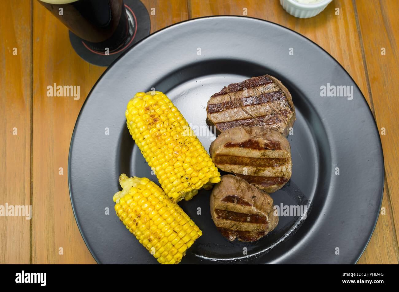 Délicieux filet mignon en gros plan avec du maïs rôti et un verre de bière. Banque D'Images