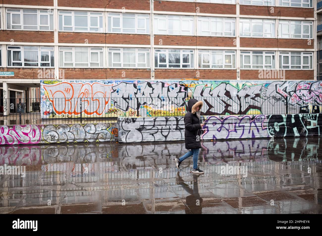 Une femme solitaire passe devant un mur de graffiti dans Old Street, East London, Royaume-Uni Banque D'Images