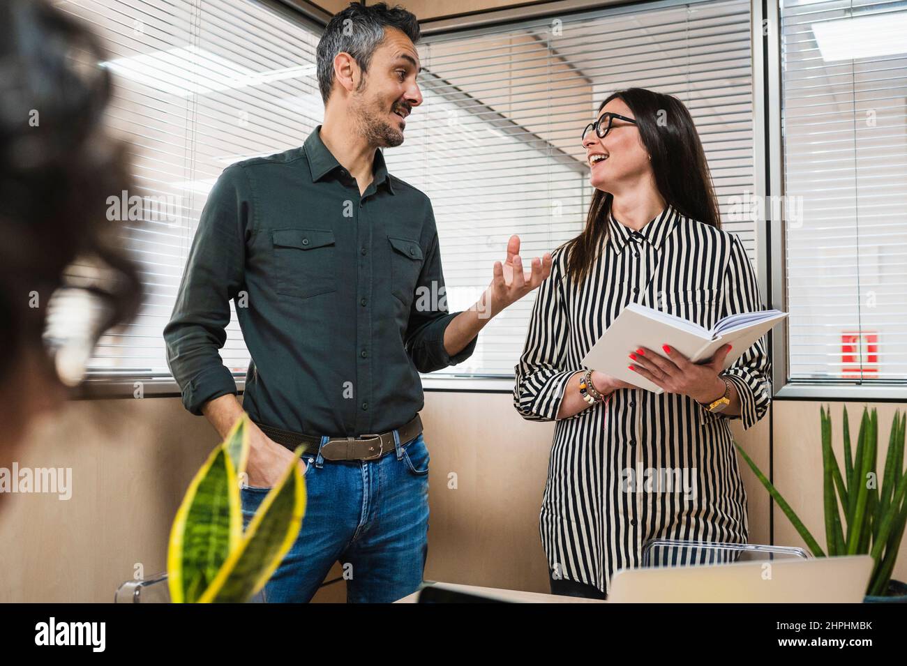 Homme et femme d'âge moyen discutant d'un projet dans une salle de bureau. Banque D'Images