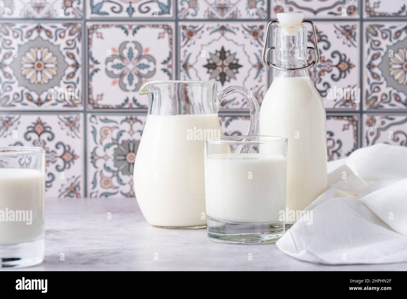 Du lait dans un verre, un carafe et un biberon sur fond clair Banque D'Images
