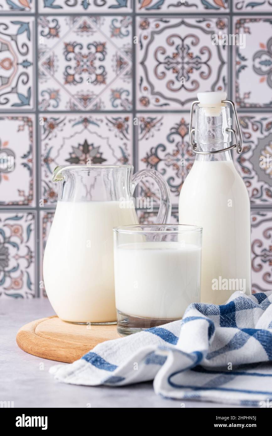 Du lait dans un verre, un carafe et un biberon sur fond clair Banque D'Images