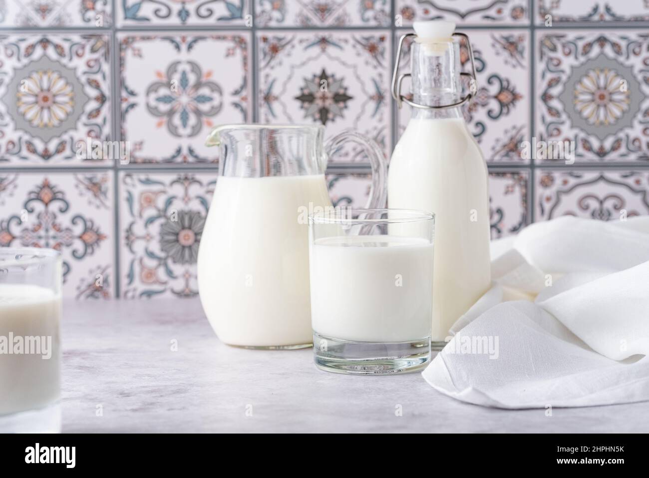 Du lait dans un verre, un carafe et un biberon sur fond clair Banque D'Images