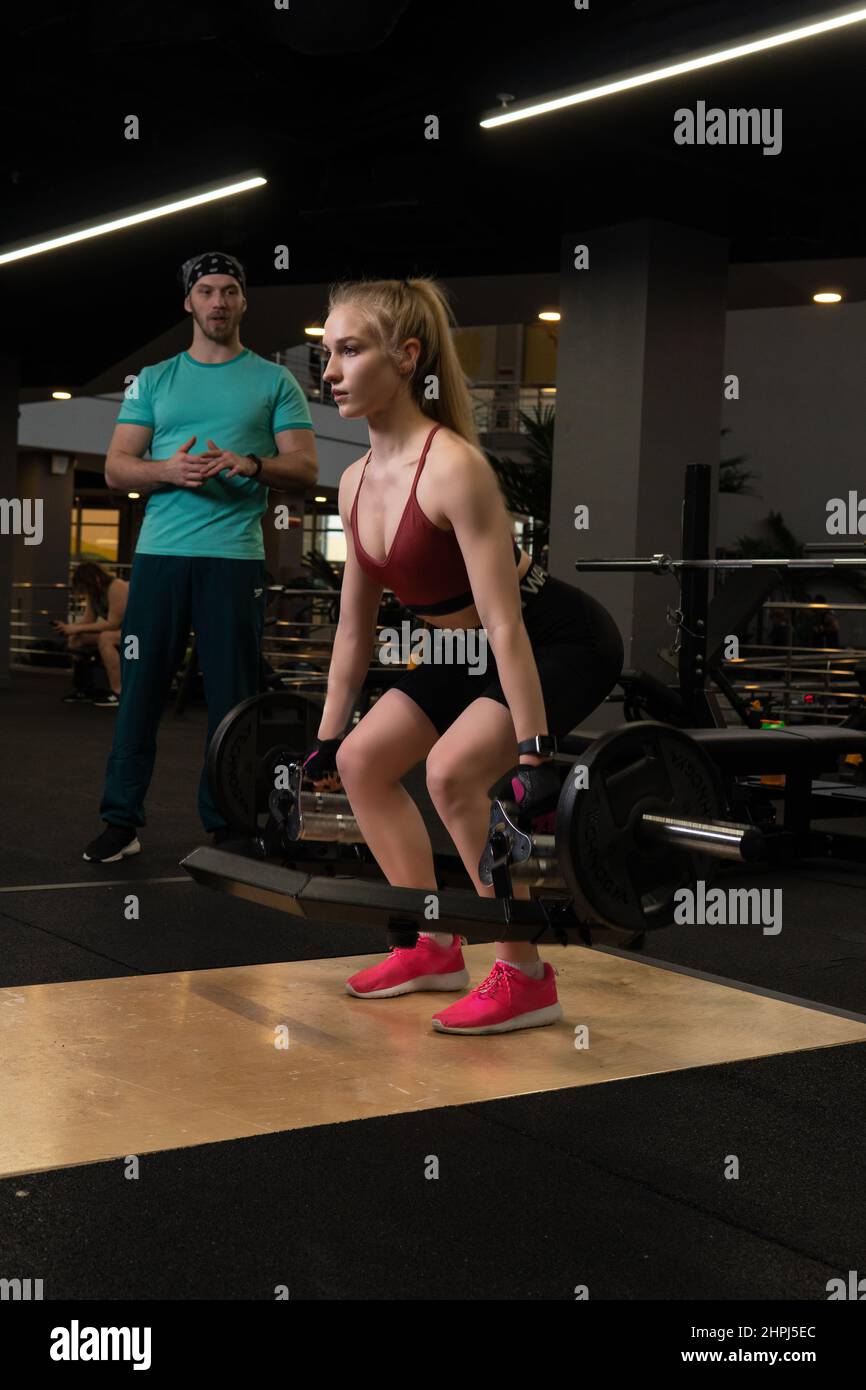 L'entraînement dirigé par un instructeur aide un beau client à effectuer des exercices dans un club de remise en forme, le concept de jouer du sport avec un loisir professionnel de gym Banque D'Images