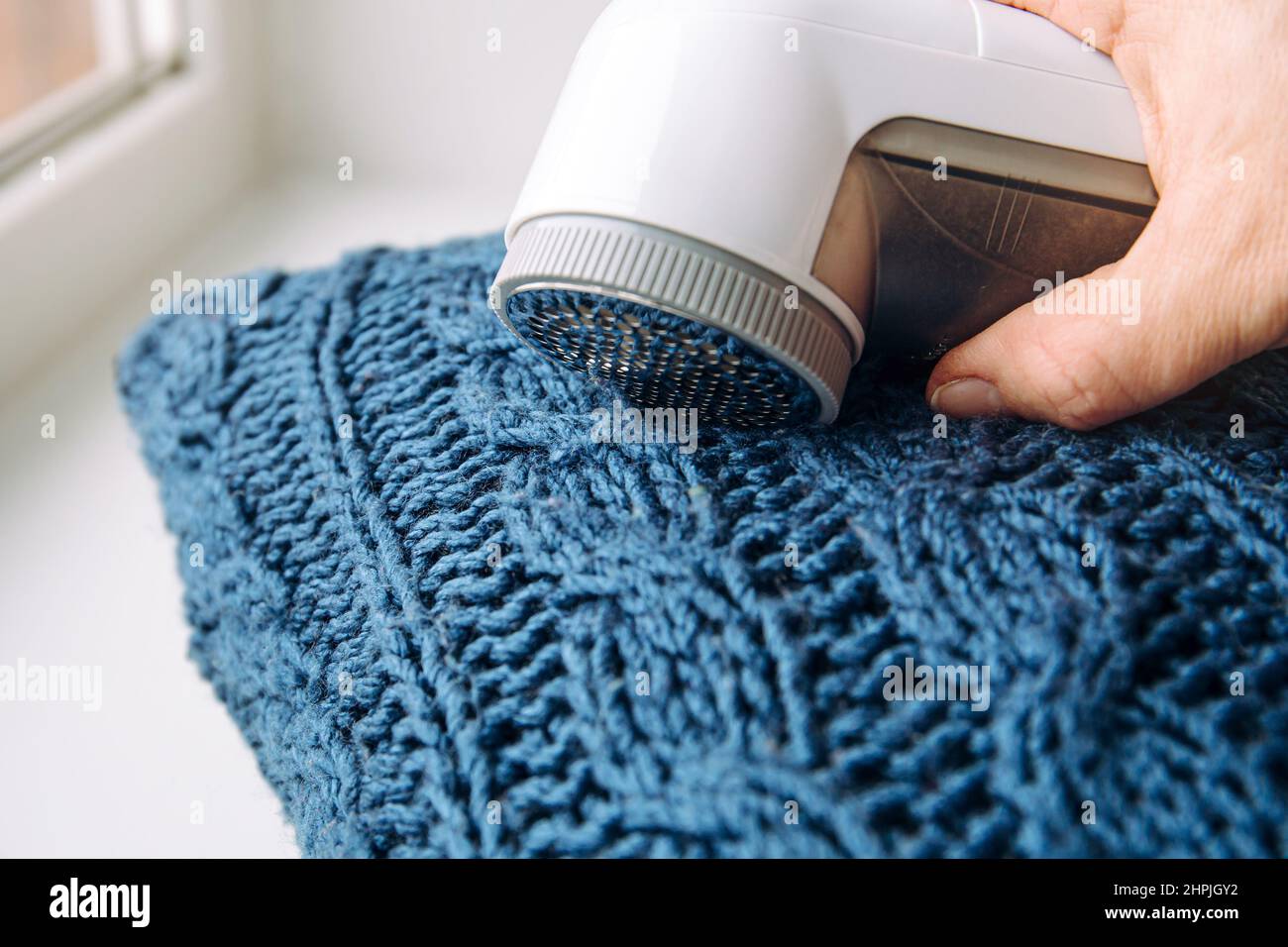 Suppression des peluches de rasage fuzz du pull bleu laine manteau, les vêtements de laine maintiennent le concept. Banque D'Images